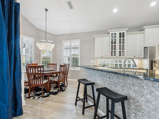 kitchen with white cabinetry, stainless steel fridge, a chandelier, pendant lighting, and light wood-type flooring