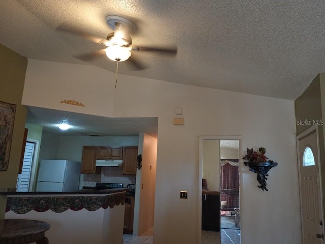 kitchen with kitchen peninsula, a textured ceiling, light tile patterned floors, white fridge, and a breakfast bar area