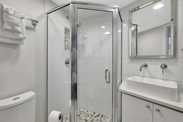 bathroom with a shower with door, vanity, and toilet