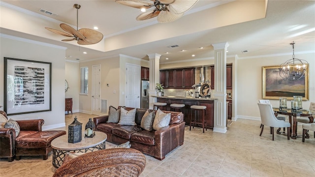 living room featuring an inviting chandelier, decorative columns, a raised ceiling, light tile patterned flooring, and ornamental molding