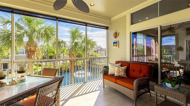 sunroom / solarium with ceiling fan and a water view