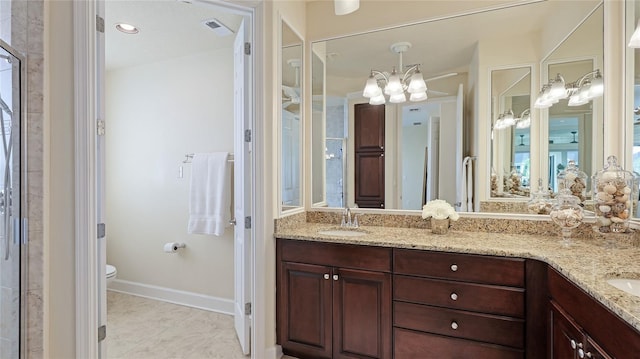 bathroom with toilet, vanity, a notable chandelier, and tile patterned flooring