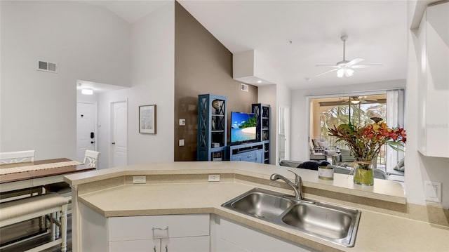 kitchen with lofted ceiling, ceiling fan, white cabinetry, and sink