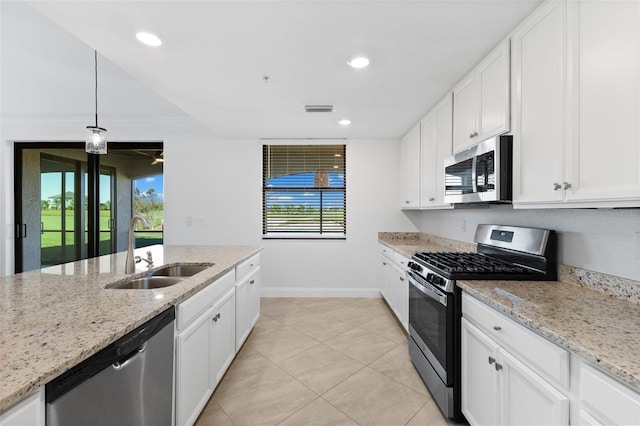 kitchen with light stone countertops, white cabinetry, sink, hanging light fixtures, and appliances with stainless steel finishes