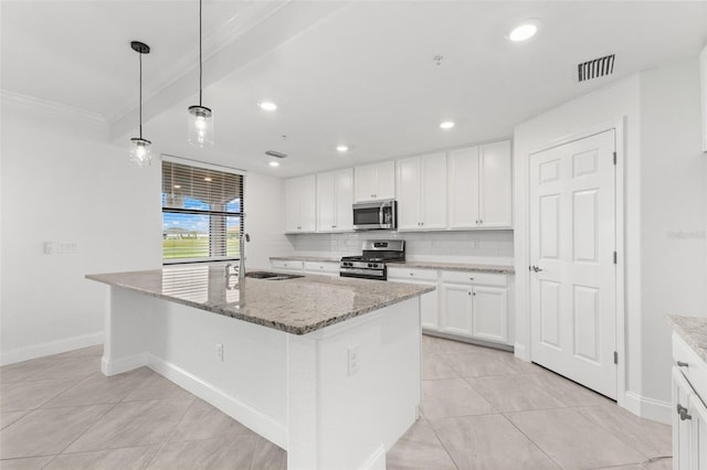 kitchen with decorative backsplash, light stone counters, a kitchen island with sink, and appliances with stainless steel finishes