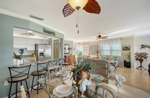 dining room with light wood-type flooring, ceiling fan, and crown molding