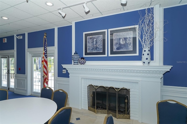 living room featuring light tile patterned floors, track lighting, and a brick fireplace