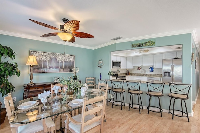 dining space featuring light wood-type flooring, ceiling fan, ornamental molding, and sink