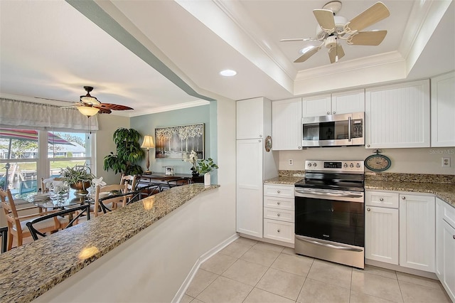 kitchen featuring a raised ceiling, light stone countertops, appliances with stainless steel finishes, light tile patterned flooring, and white cabinetry