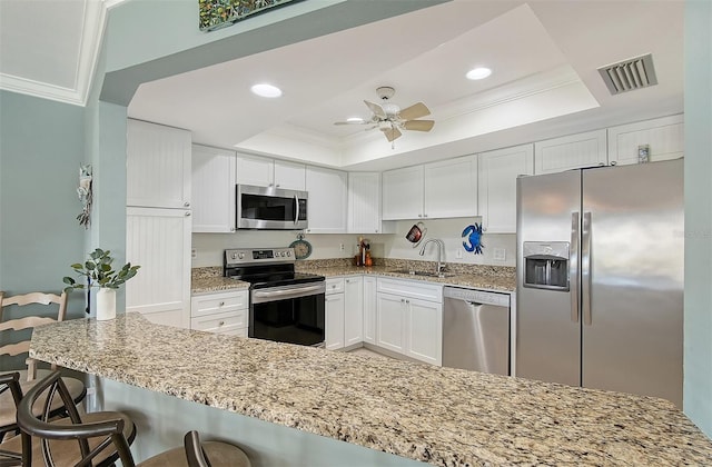 kitchen with white cabinets, appliances with stainless steel finishes, and a tray ceiling