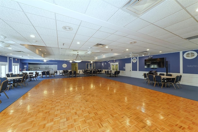 gym featuring a paneled ceiling and parquet floors