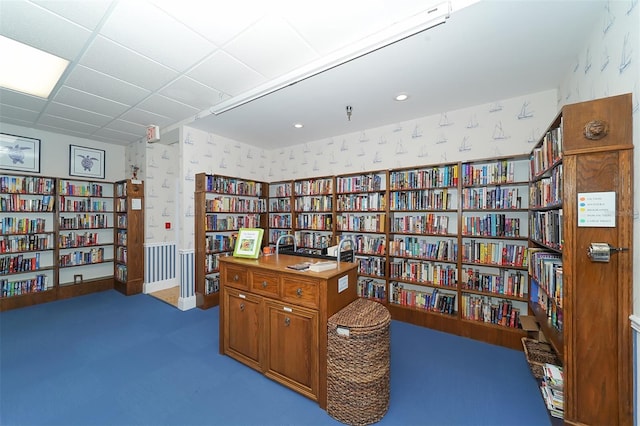 living area featuring carpet and a paneled ceiling