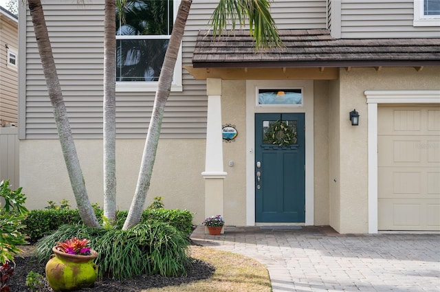 entrance to property featuring a garage and stucco siding