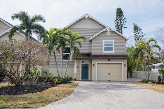 view of front of home with decorative driveway, stucco siding, an attached garage, and fence