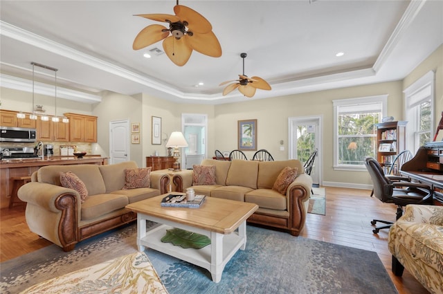 living room featuring baseboards, a raised ceiling, a ceiling fan, and hardwood / wood-style floors