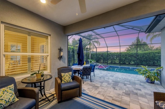 patio terrace at dusk with pool water feature, a fenced in pool, glass enclosure, and ceiling fan