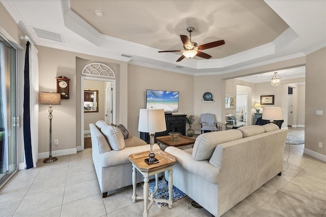 living room featuring ceiling fan, a raised ceiling, ornamental molding, and light tile patterned floors