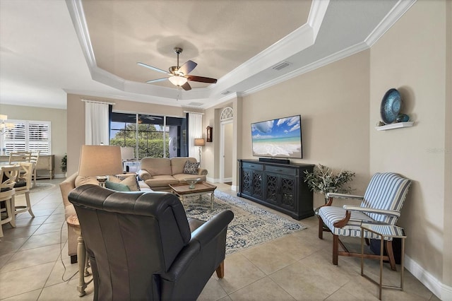 tiled living room with ceiling fan, ornamental molding, and a tray ceiling