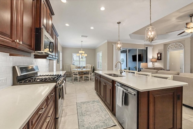 kitchen featuring decorative light fixtures, stainless steel appliances, a kitchen island with sink, and sink