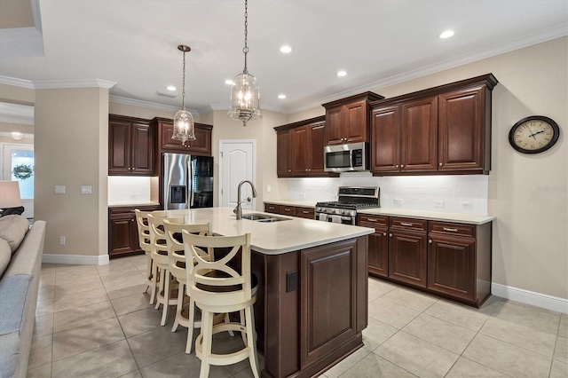 kitchen featuring sink, stainless steel appliances, decorative light fixtures, a kitchen island with sink, and a breakfast bar