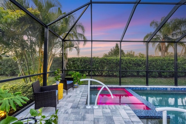 pool at dusk with a patio area and a lanai