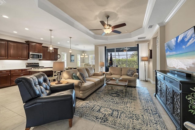 living room with a raised ceiling, crown molding, light tile patterned floors, and ceiling fan with notable chandelier