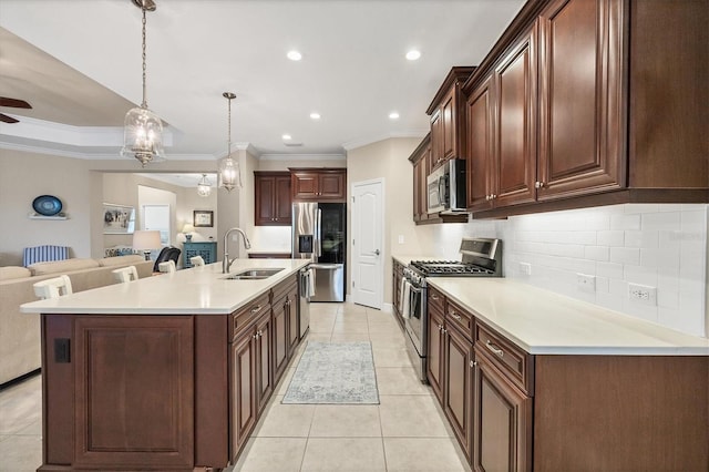 kitchen with a large island with sink, sink, hanging light fixtures, ornamental molding, and stainless steel appliances