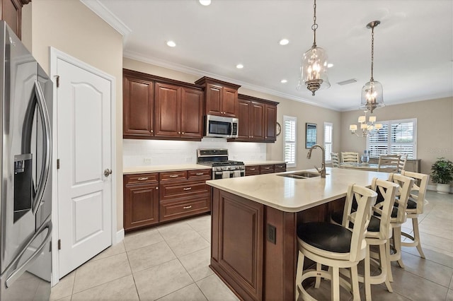 kitchen featuring sink, hanging light fixtures, a kitchen breakfast bar, a center island with sink, and appliances with stainless steel finishes