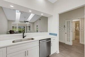 kitchen featuring white cabinets, hardwood / wood-style flooring, stainless steel dishwasher, and sink