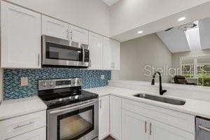 kitchen featuring kitchen peninsula, sink, white cabinets, and stainless steel appliances