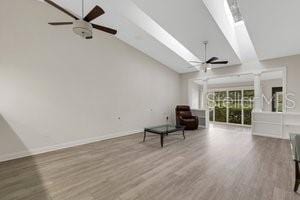 unfurnished room with hardwood / wood-style floors, ceiling fan, and vaulted ceiling with skylight