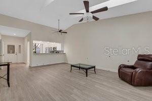 living room with ceiling fan, light wood-type flooring, and vaulted ceiling