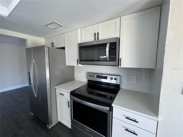 kitchen featuring white cabinets, a textured ceiling, stainless steel appliances, and tasteful backsplash