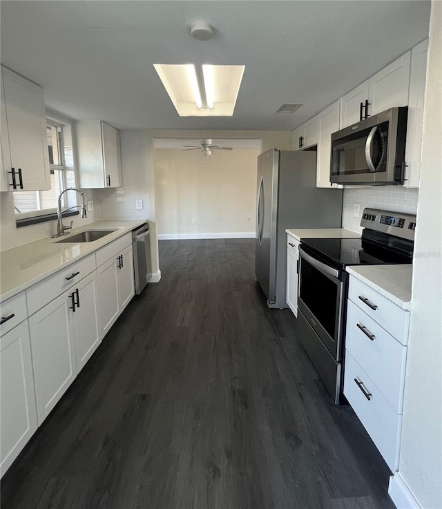 kitchen featuring backsplash, stainless steel appliances, dark wood-type flooring, sink, and white cabinetry