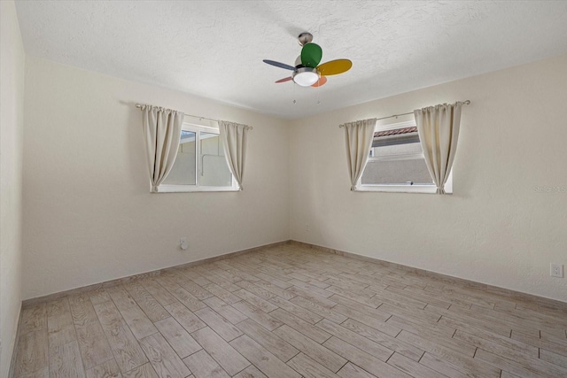 spare room featuring a textured ceiling, light wood-type flooring, and ceiling fan