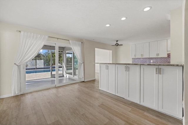 kitchen featuring decorative backsplash, kitchen peninsula, ceiling fan, stone countertops, and white cabinets