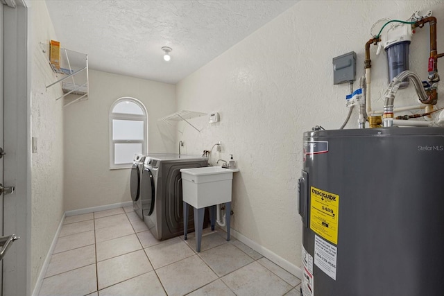 washroom with light tile patterned floors, washing machine and dryer, a textured ceiling, and water heater