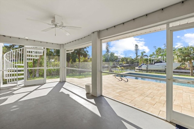 unfurnished sunroom with ceiling fan, a healthy amount of sunlight, and a water view