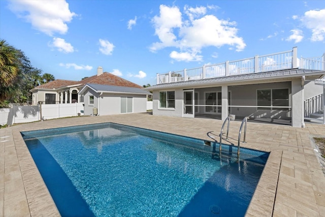 back of house with a fenced in pool, a sunroom, a balcony, and a patio