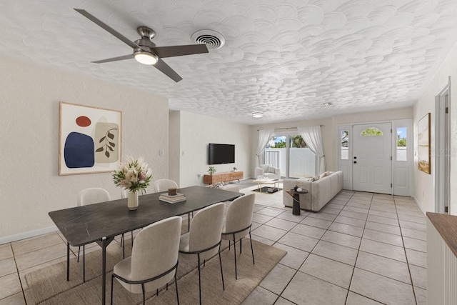 dining room featuring a textured ceiling, a textured wall, light tile patterned flooring, visible vents, and baseboards