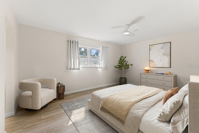 bedroom with light wood-style floors, ceiling fan, and baseboards