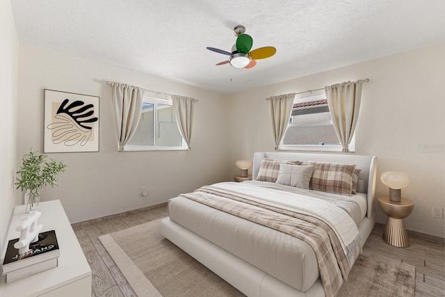 bedroom featuring a textured ceiling, multiple windows, and light wood-type flooring