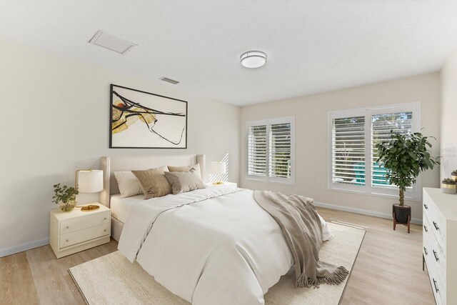 bedroom with light wood-type flooring, visible vents, and baseboards