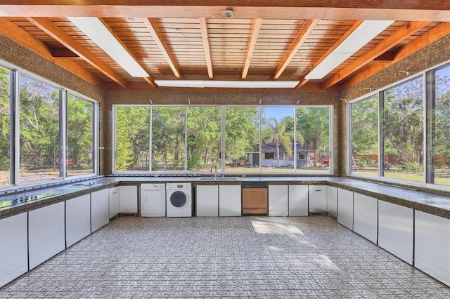 unfurnished sunroom with washer / clothes dryer, a skylight, and sink