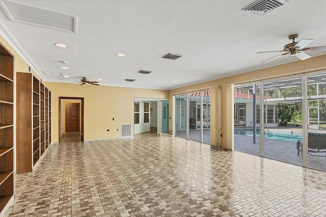 interior space featuring crown molding, wooden walls, and ceiling fan