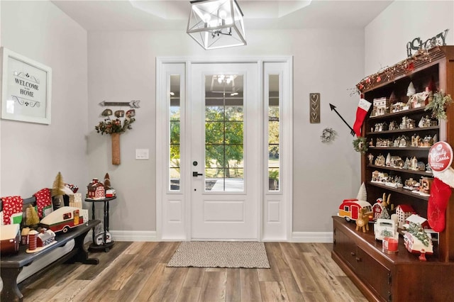 entrance foyer with a notable chandelier, a raised ceiling, and light wood-type flooring