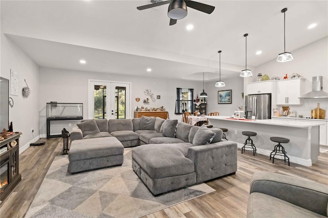 living room featuring ceiling fan, vaulted ceiling, and light wood-type flooring