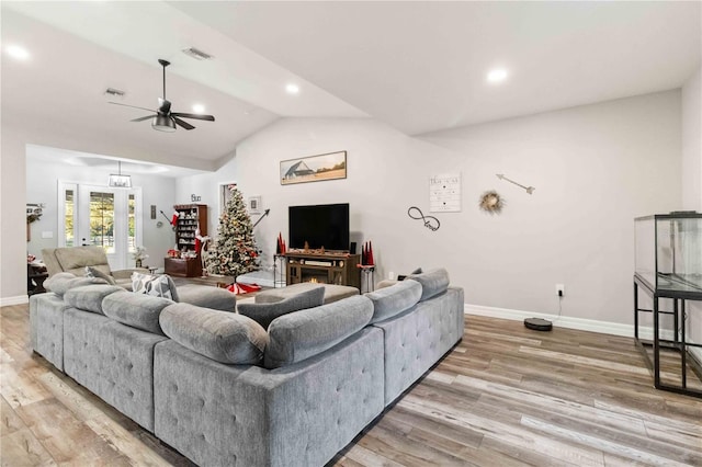 living room with hardwood / wood-style flooring, ceiling fan, and vaulted ceiling