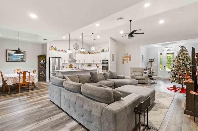 living room with ceiling fan, light hardwood / wood-style flooring, vaulted ceiling, and sink