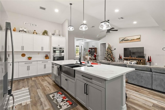 kitchen with tasteful backsplash, white cabinetry, pendant lighting, and a kitchen island with sink